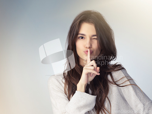 Image of Woman, studio portrait and secret with finger on mouth for beauty deal, wink eye or icon for silence by background. Isolated model girl, cosmetics flirt or hand sign with emoji, whisper and makeup