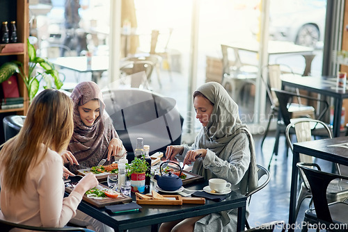 Image of Muslim women, talking and lunch in restaurant, together or friends with food, smile or happiness. Islamic woman, hungry group and brunch with social conversation, eating or listening to chat in cafe