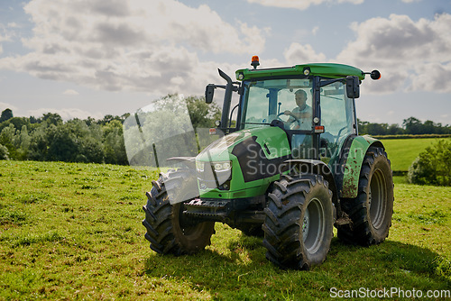 Image of Man, farm and green tractor on grass in countryside for agriculture, lawn or sustainability in nature. Male person or farmer in big agricultural machinery for farming, ecology or construction on land