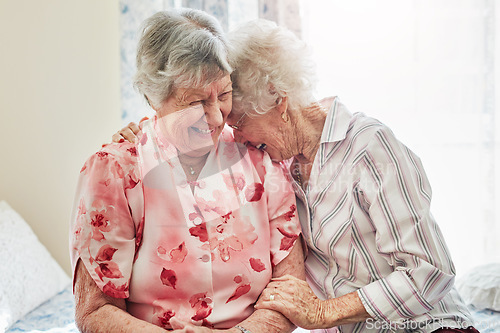 Image of Happy, funny and senior woman friends laughing in the bedroom of a retirement home together. Smile, comedy and laughter with an elderly female pensioner and friend bonding indoor during a visit