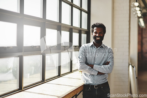 Image of Portrait, window and a business man arms crossed in the office with a smile or mindset of future success. Flare, vision and corporate with a happy male employee standing at work during his break