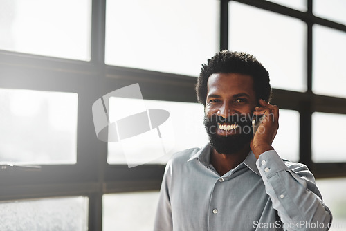 Image of Portrait, window and phone call with a business man in the office for communication or networking. Face, happy and contact with a happy male employee networking in the workplace during his break