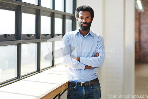 Image of Portrait, window and a business man arms crossed in the office with a mindset of focus on future success. Serious, vision and corporate with a male employee standing in the workplace during his break