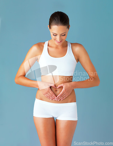 Image of Heart, hands on abdomen and woman with gut health and wellness isolated on blue background. Weight loss, fitness and healthy female person with self love and body care in studio with diet