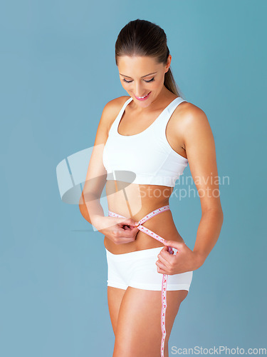 Image of Woman, measuring tape and health, diet with waist size from weight loss isolated on blue background. Healthy, tummy tuck and body measurement with female person in studio with wellness and fitness