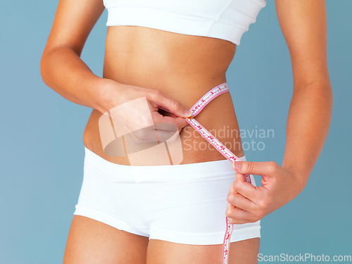 Image of Woman, measuring tape and lose weight, health and diet with waist size isolated on blue background. Healthy, tummy tuck and body measurement with female person in studio with wellness and fitness