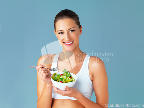 Image of Woman in portrait, smile and eating salad, diet and healthy food with weight loss isolated on blue background. Health, wellness and nutrition with vegetables, female model in studio and mockup space