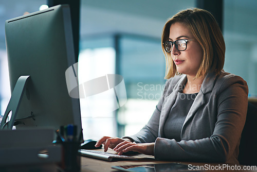 Image of Computer, business woman and typing in office, working late on project and focus at night. Desktop, professional and female person writing email, report or planning, reading and overtime for deadline