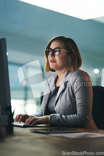 Image of Desktop, typing and business woman in office, working late on project and focus at night. Computer, professional and female person writing email, report or planning, reading and overtime for deadline