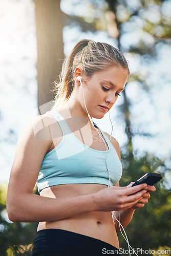 Image of Woman with earphones, smartphone and fitness with music outdoor, listening for motivation on run in park. Female runner with song choice, podcast or radio streaming with exercise, focus and health