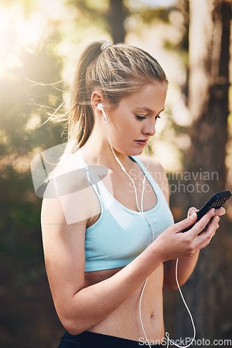 Image of Woman with earphones, phone and fitness with music outdoor, listening for motivation on run in park. Female runner with song choice on mobile, podcast or radio streaming for exercise and health