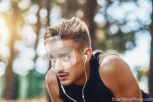 Image of Man with earphones, breathing after running in forest and fitness with music, listening for motivation on run in park. Male runner outdoor, rest with podcast or radio streaming, exercise and cardio