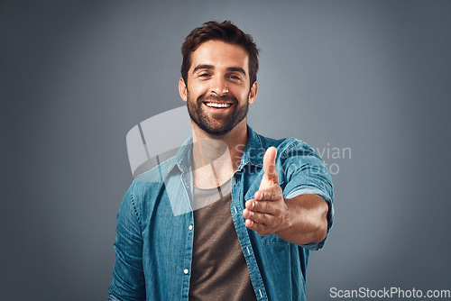 Image of Happy man, portrait and handshake for introduction, welcome or greeting against a grey studio background. Male person shaking hands with smile for promotion, meeting or deal agreement on mockup space