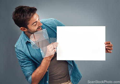 Image of Man, billboard sign and mockup for marketing, advertising or branding against a grey studio background. Male person holding rectangle shape poster or placard for advertisement message with copy space