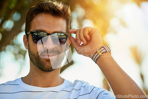 Image of Happy, sunglasses and portrait of a man in an outdoor park while on a summer vacation, adventure or holiday. Smile, confidence and young male person with eyewear standing in a garden on weekend trip.