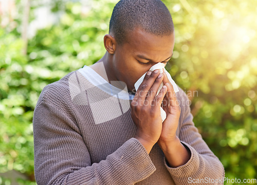 Image of Blowing nose, hay fever and allergy with black man in park for spring, virus and sickness. Illness, spring and wellness with male person and tissue in nature for allergies, flu and congestion