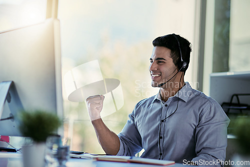 Image of Callcenter agent, smile and winning, man with advice, celebration and happiness at help desk. Happy phone call, conversation and success, customer support consultant speaking into headset in office.