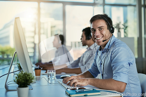 Image of Customer service, coworking space and portrait of happy man consulting with advice and smile at help desk. Phone call, conversation and happiness, callcenter consultant typing at computer in office.