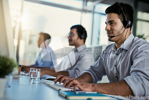 Image of Crm agent, smile and man in coworking space consulting with advice and happiness at help desk. Happy phone call, conversation and customer support consultant speaking on headset in callcenter office.