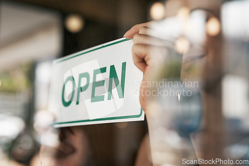 Image of Open, sign and window with hands of person for coffee shop, restaurant and retail. Shopping, start and ready with closeup of employee and poster at door for cafe, small business and store