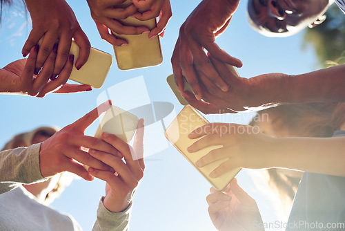 Image of Hands, low angle and phone by friends together for social media, networking and sharing app on blue sky background. Below, smartphone and gen z people with internet, addiction or online communication