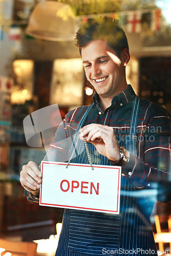 Image of Open sign, smile and man with business, startup success and service with restaurant, window and coffee shop. Male person, employee and entrepreneur with billboard, poster and opening retail store