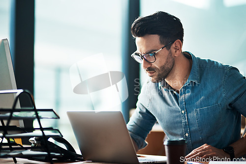 Image of Serious, business man and laptop in office for planning, online research or developer reading data at desk. Focused worker, computer and website connection for digital project, internet or technology