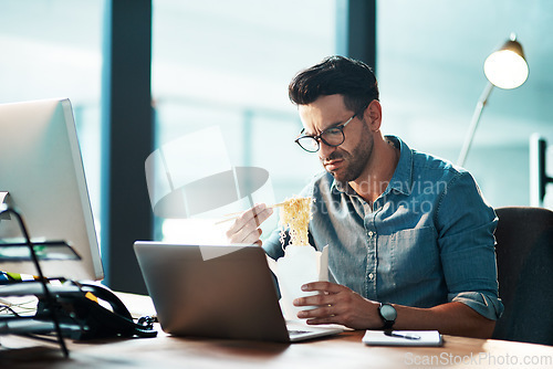 Image of Unhappy business man eating noodles in office at laptop in startup agency with disgust, upset or problem. Frustrated, sad and angry male employee with bad fast food at computer for working in company