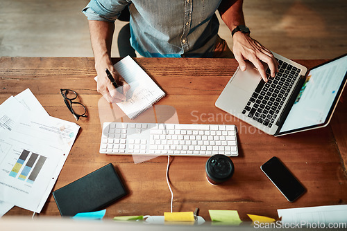 Image of Top view, laptop and business man writing notes for planning, strategy and online data analysis at office desk. Worker, computer and notebook for trading, research and productivity in startup agency