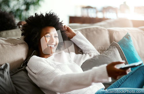 Image of Black woman, watching tv and relax on sofa with remote, smile and happiness for film, comedy or show. African girl, television and happy for movie, video and browsing on lounge couch in apartment