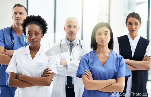 Image of Healthcare, crossed arms and portrait of team of doctors standing in the hallway with confidence. Serious, diversity and group of medical workers in the corridor of a medicare clinic or hospital.