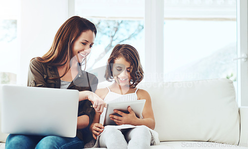 Image of Technology, mother on laptop and helping daughter on tablet sitting on sofa in the living room of their home. Social media or connectivity, networking or streaming and woman with child happy on couch