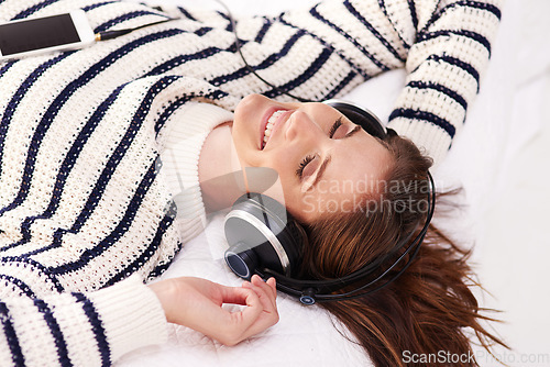 Image of Smile, listening to music and happy woman on bed with headphones from above, happiness and wellness in home. Audio, relax and girl in bedroom with streaming radio service or podcast in apartment.