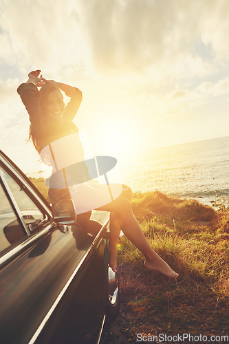 Image of Road trip, portrait and sunset with a woman at the coast, sitting on her car bonnet during travel for freedom or escape. Nature, lens flare and water with a young female tourist traveling in summer