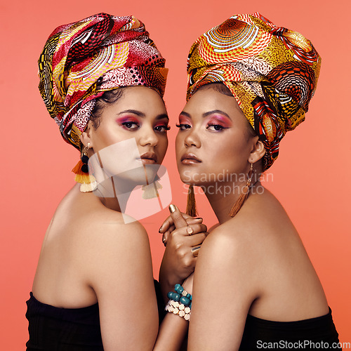 Image of African fashion, makeup and portrait of women on orange background with accessory, makeup and beauty. Glamour, luxury and female people in exotic jewelry, traditional style and head scarf in studio