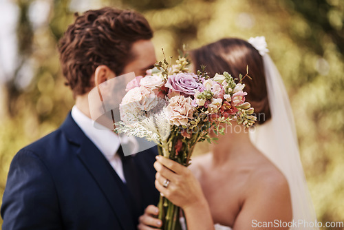 Image of Flowers, wedding and a married couple behind a bouquet together after a ceremony of tradition outdoor. Love, marriage or commitment with a man and woman outside as husband and wife in matrimony