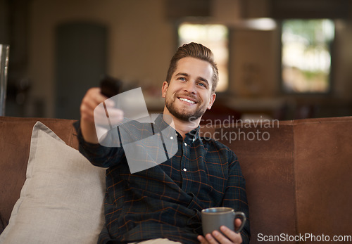 Image of Relax, coffee and a man watching tv on a sofa in the living room of his home with a remote for streaming. Smile, tea and a happy young male person using a subscription service on his television