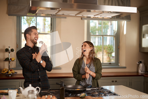 Image of Food, sing and a silly couple in the kitchen of their home, having fun together while cooking. Karaoke, comic or funny with a man and woman laughing while singing over breakfast in their house