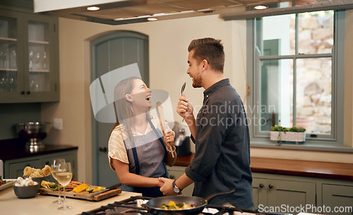 Image of Love, home and couple in a kitchen, happiness and playful with joy, bonding and loving together. Partners, man and woman with affection, house or singing with humor, relationship or marriage with fun