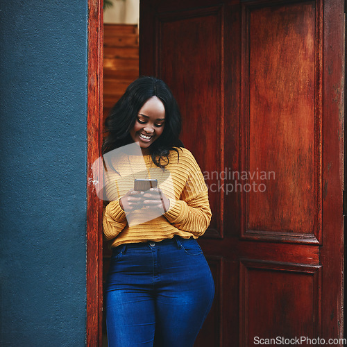 Image of Phone, door and black woman in front of home with social media, smile and streaming or typing. Smartphone, property and female travel influencer with online review for accommodation or rental app