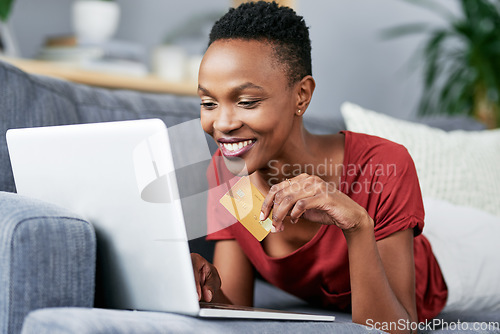 Image of Laptop, credit card and black woman relax on a sofa for online shopping, e commerce and membership. Banking, credit score and female African person happy with payment, booking or customer experience