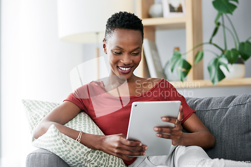 Image of Digital tablet, relax and happy black woman on a sofa for social media, reading and browsing blog in her home. Smile, online and African female person on couch with ebook, streaming or subscription