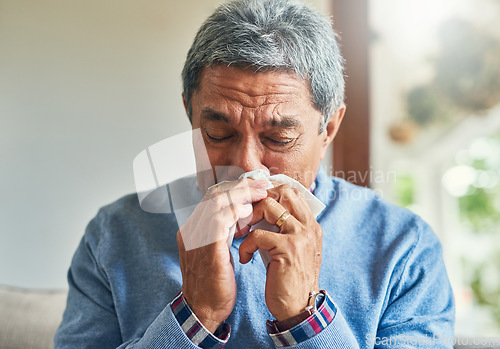 Image of Senior man, sick and blowing nose in home from virus, allergy and illness on couch. Tired, tissue and elderly male person in a house lounge with sneeze from covid and flu on a sofa with allergies