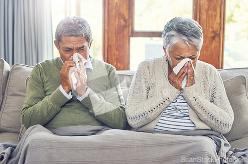 Image of Senior couple, sick and blowing nose in home from virus, allergy and illness on living room couch. Tired, tissue and elderly people in a house lounge with sneeze from flu and cough on a sofa together