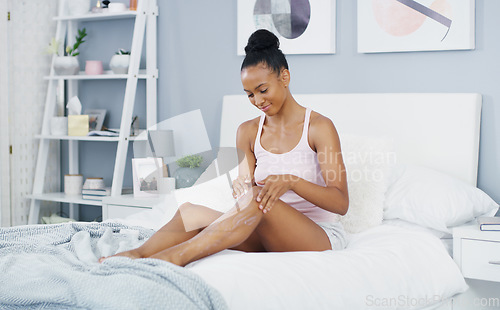 Image of Woman, leg and moisturizer in bed for body care and cleaning in a home in morning lotion. Smile, relax and skincare with happy African female person with skin beauty and cosmetics cream in a house