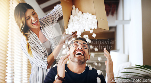 Image of Moving house, property and box with a silly married couple having fun while playing in their new home together. Real estate, comic or comedy with a playful husband and wife joking in the living room