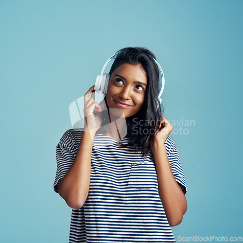 Image of Music, young Indian woman with headphones and smile in studio background. Technology or entertainment, sound track and happy female person listen to radio or audio podcast isolated in backdrop