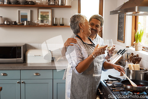 Image of Cheers, wine and senior couple in kitchen cooking healthy food together on stove with smile, health and romance. Toast, drinks and old woman with man, glass and happiness, meal in pan and retirement.