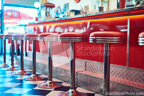 Image of Trendy, vintage and retro interior in a diner, restaurant or cafeteria with funky decor. Booth, old school and chairs by a counter or bar in a groovy, vibrant and stylish old fashioned empty cafe.