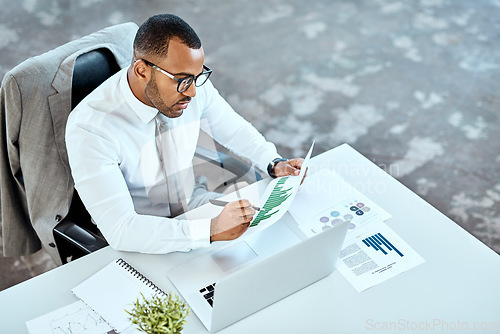 Image of Financial analyst, focus and black businessman planning in an office or reading report and employee on desk. Serious, corporate worker and graphs or revenue documents or laptop and stats data at work